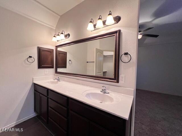 full bath featuring ceiling fan, double vanity, baseboards, and a sink