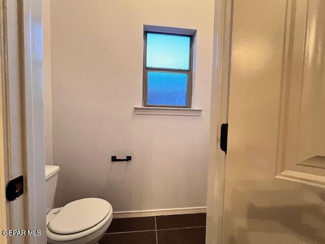 bathroom featuring tile patterned flooring, toilet, a shower, and baseboards