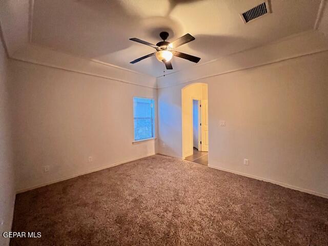 empty room featuring visible vents, arched walkways, ceiling fan, and carpet flooring