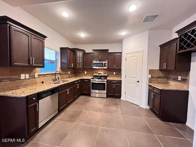 kitchen featuring visible vents, light tile patterned flooring, a sink, dark brown cabinetry, and appliances with stainless steel finishes