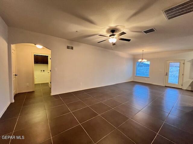 empty room featuring visible vents, arched walkways, and ceiling fan with notable chandelier