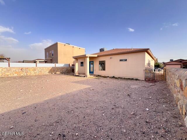 rear view of property featuring stucco siding and a fenced backyard