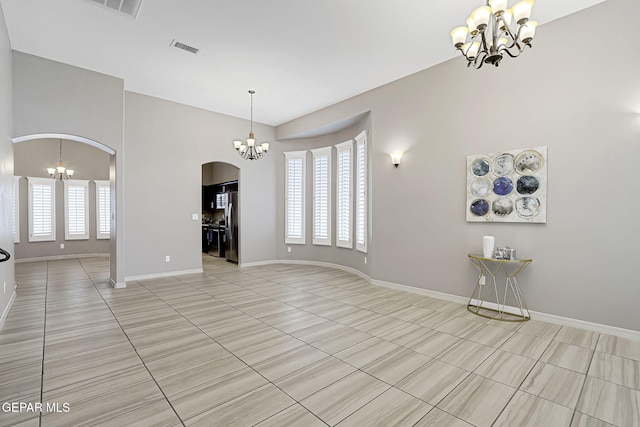 unfurnished living room featuring a wealth of natural light, baseboards, arched walkways, and a notable chandelier