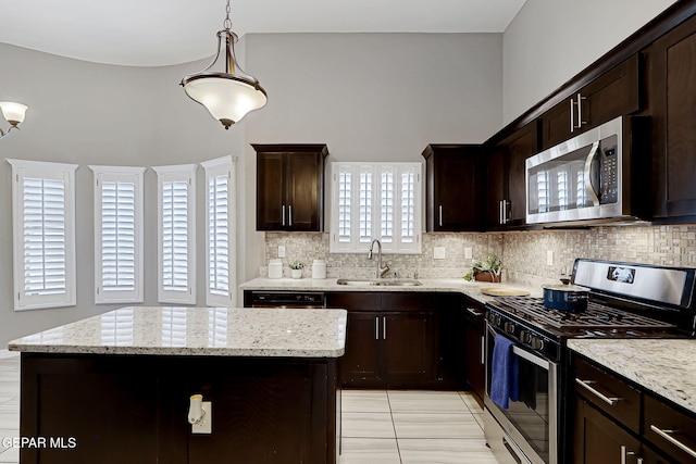 kitchen featuring a sink, light stone counters, backsplash, and appliances with stainless steel finishes