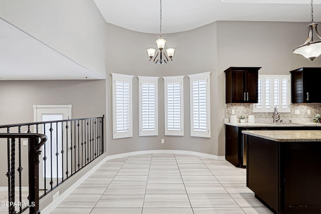 kitchen with a sink, backsplash, dark brown cabinets, a chandelier, and hanging light fixtures