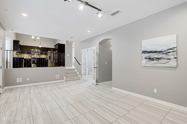 unfurnished living room with visible vents, baseboards, recessed lighting, arched walkways, and stairs