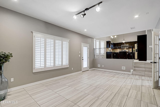 interior space featuring an inviting chandelier, rail lighting, recessed lighting, and baseboards