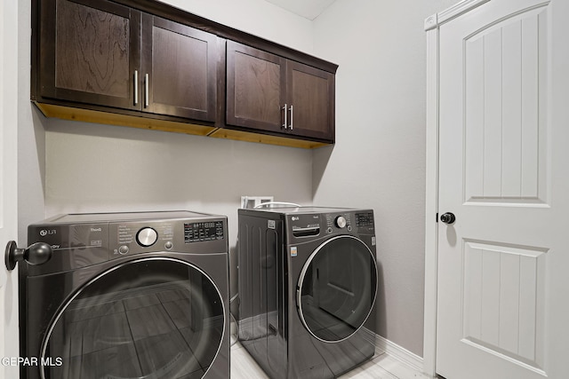 washroom featuring baseboards, cabinet space, and separate washer and dryer