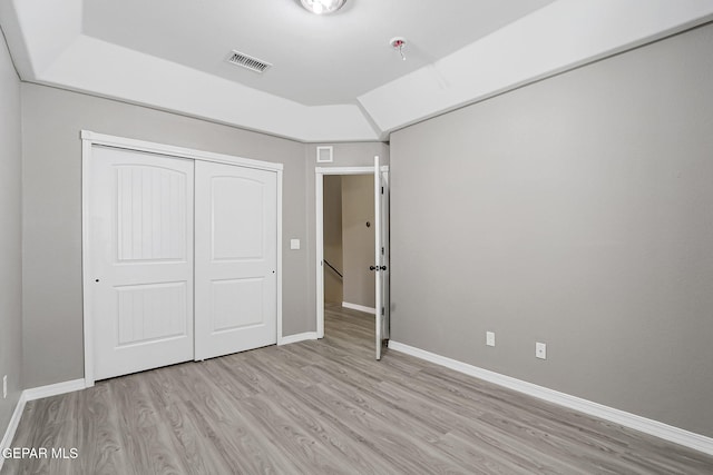 unfurnished bedroom featuring visible vents, baseboards, light wood-style floors, and a closet