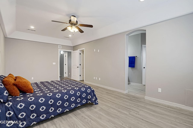 bedroom with visible vents, wood finished floors, arched walkways, and baseboards