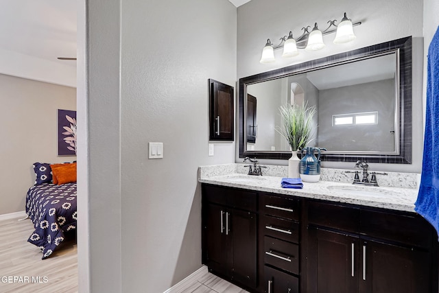 bathroom with a sink, baseboards, and double vanity