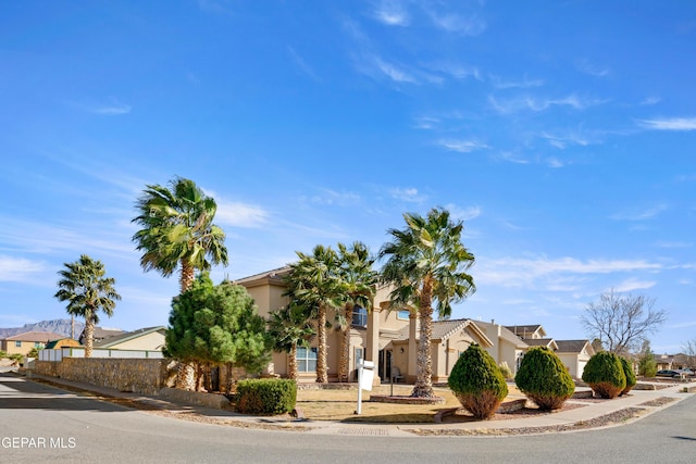 view of front of property with fence, a residential view, and stucco siding