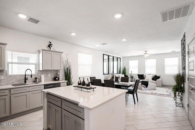 kitchen featuring visible vents, gray cabinetry, a sink, tasteful backsplash, and light countertops