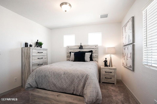 carpeted bedroom featuring multiple windows, baseboards, and visible vents