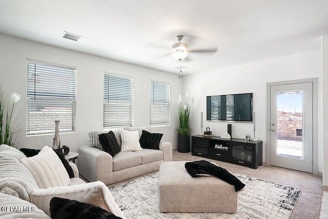 living room with light colored carpet, visible vents, a wealth of natural light, and ceiling fan