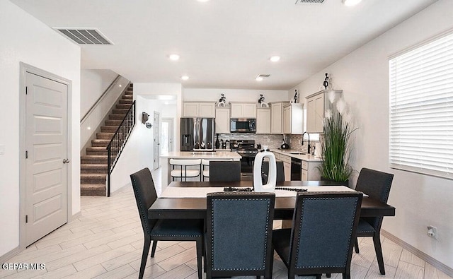dining area with light wood finished floors, visible vents, recessed lighting, and stairs