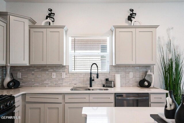 kitchen with stainless steel dishwasher, light countertops, tasteful backsplash, and a sink