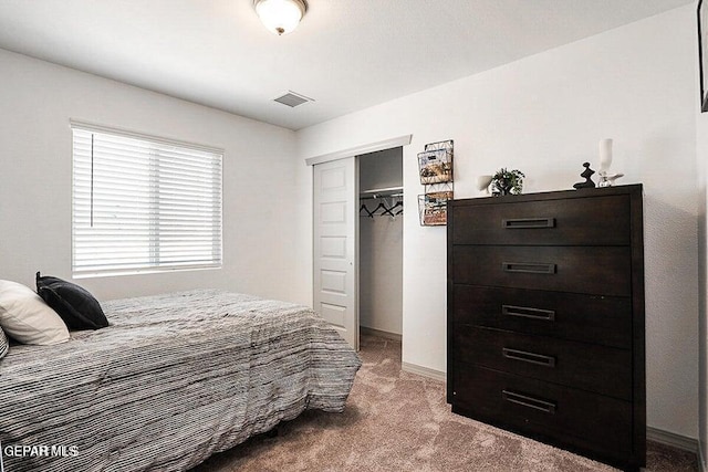 carpeted bedroom with visible vents, a closet, and baseboards