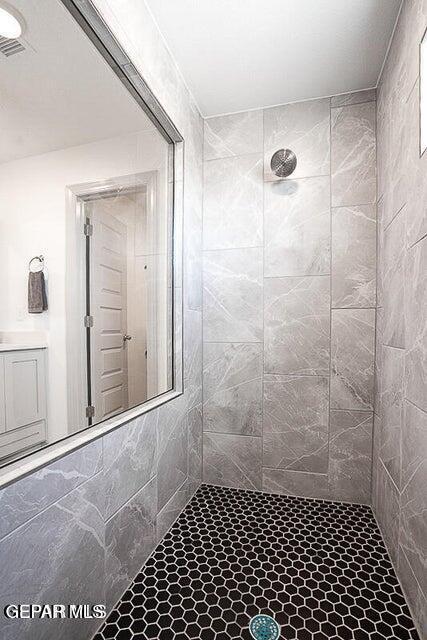 full bath with visible vents and tiled shower