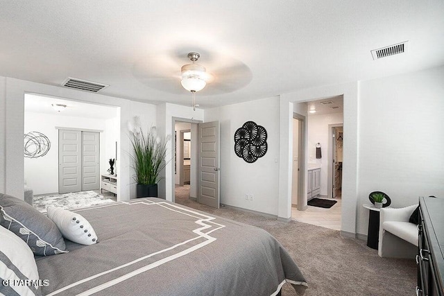 bedroom with baseboards, visible vents, ensuite bath, and carpet