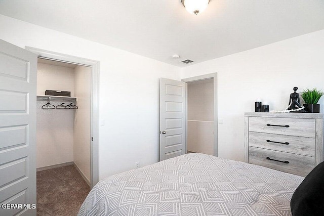 bedroom with a closet, dark carpet, and a spacious closet