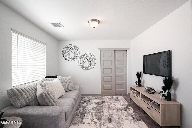 living area featuring dark colored carpet, visible vents, and baseboards