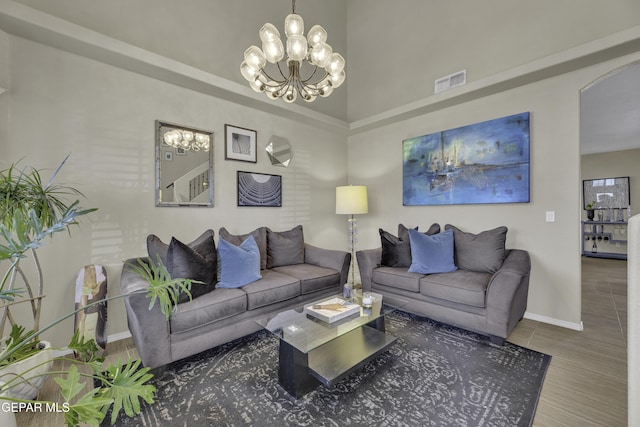 living area featuring visible vents, arched walkways, baseboards, and a chandelier