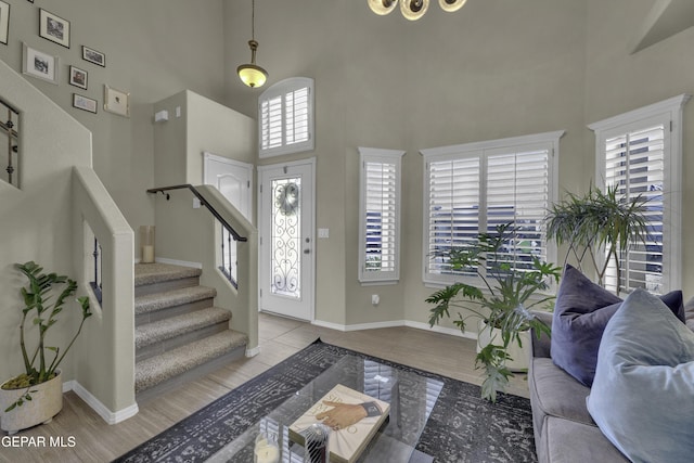 tiled entryway with stairs, a high ceiling, and baseboards