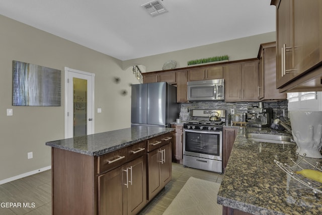 kitchen with tasteful backsplash, visible vents, a center island, appliances with stainless steel finishes, and a sink