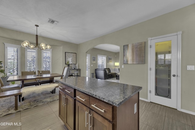 kitchen with visible vents, a notable chandelier, a kitchen island, arched walkways, and hanging light fixtures