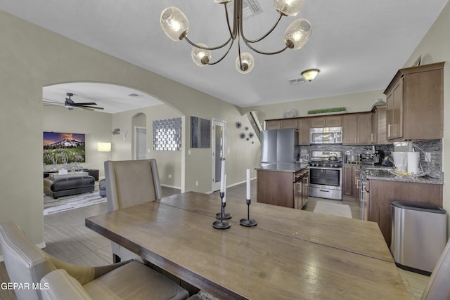 dining room featuring visible vents, ceiling fan with notable chandelier, and arched walkways