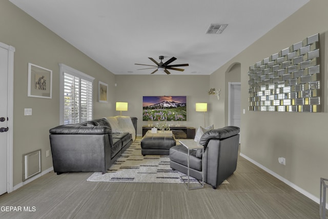 living area with baseboards, arched walkways, visible vents, and a ceiling fan