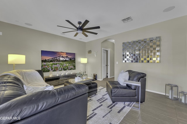 living area featuring a ceiling fan, visible vents, baseboards, arched walkways, and tile patterned flooring