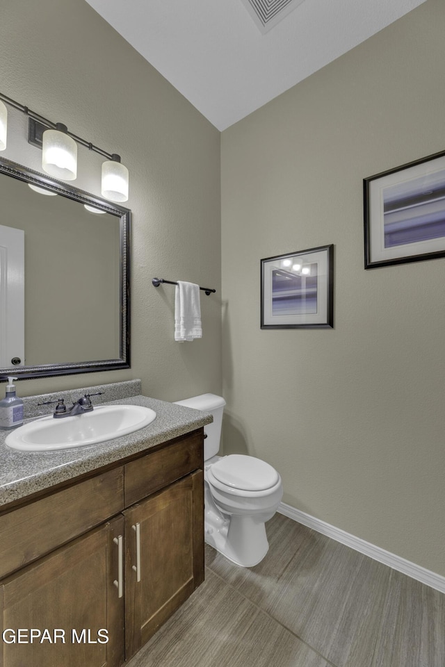 bathroom with vanity, toilet, visible vents, and baseboards