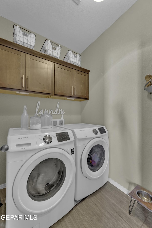 clothes washing area with baseboards, cabinet space, independent washer and dryer, and light wood finished floors