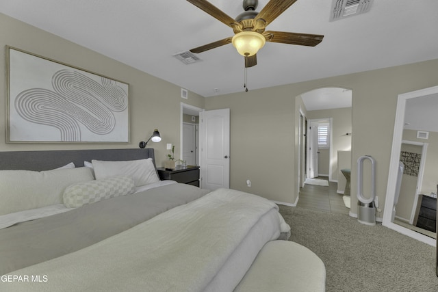 bedroom with arched walkways, visible vents, and carpet flooring