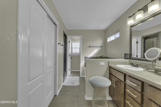 bathroom featuring vanity, a healthy amount of sunlight, a stall shower, and baseboards