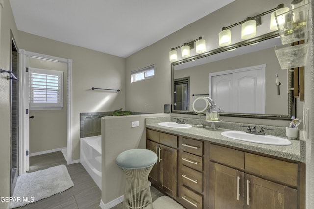 full bathroom featuring a garden tub, double vanity, baseboards, and a sink