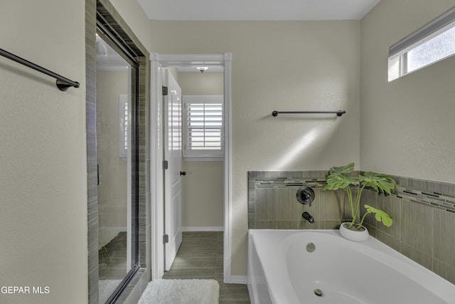 full bathroom with a wealth of natural light, baseboards, walk in shower, and a bath