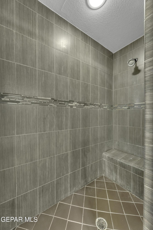 bathroom featuring a textured ceiling, tile patterned floors, and tiled shower