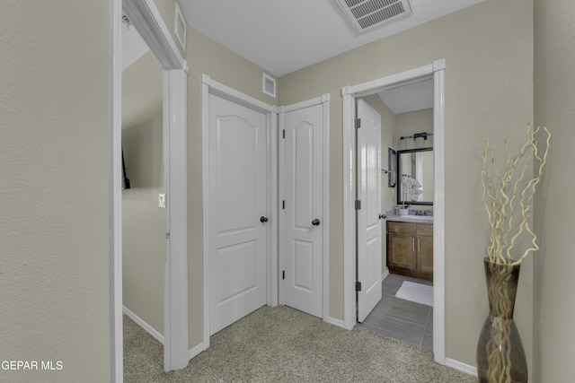 corridor featuring light carpet, visible vents, and baseboards