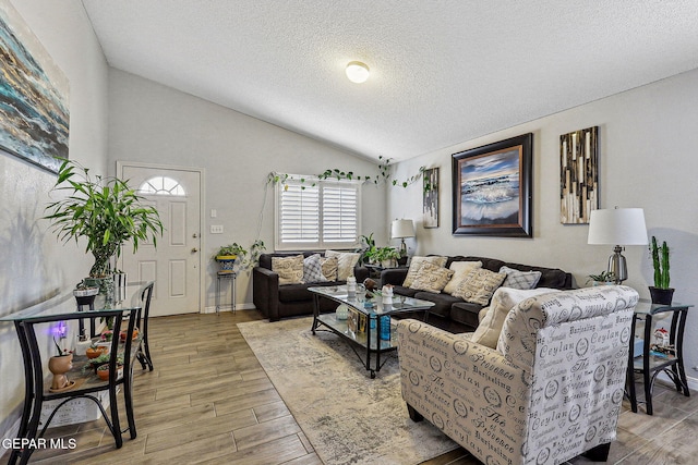 living area with lofted ceiling, light wood-type flooring, and a textured ceiling