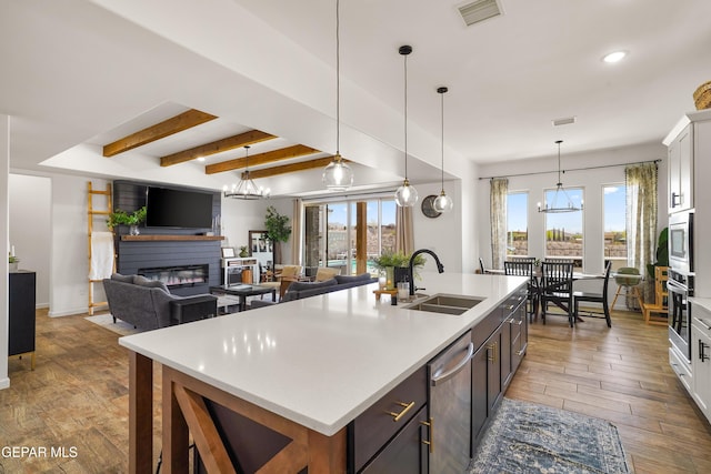 7402 Wooden Nickel Dr, El Paso, TX 79911 - kitchen featuring a sink, a fireplace, wood finished floors, appliances with stainless steel finishes, and visible vents
