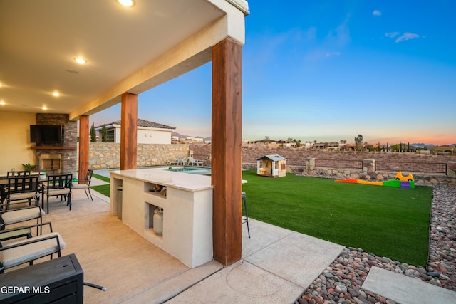 7402 Wooden Nickel Dr, El Paso, TX 79911 - view of patio / terrace with an outdoor stone fireplace, exterior kitchen, and a fenced backyard