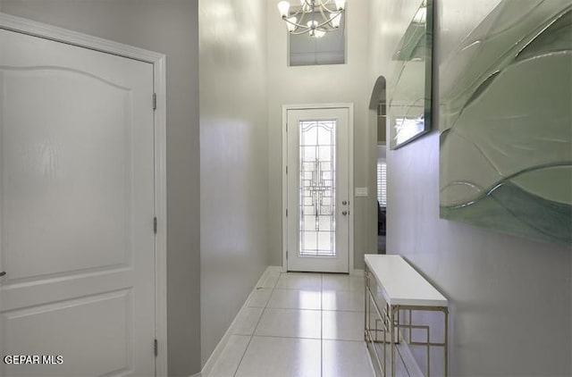 entryway with baseboards, a notable chandelier, and light tile patterned flooring