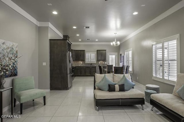 living room featuring light tile patterned flooring, a notable chandelier, and ornamental molding