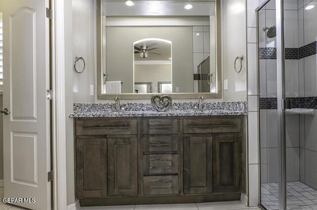 bathroom featuring a sink, a shower stall, ceiling fan, and double vanity