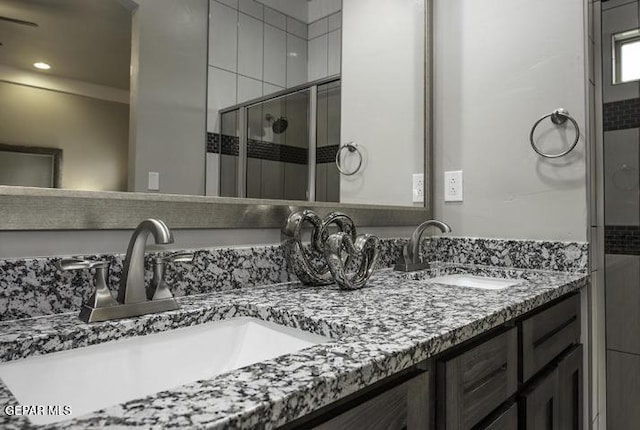 bathroom featuring a sink, double vanity, and a shower stall