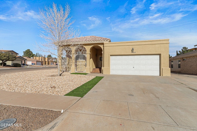 mediterranean / spanish-style home featuring stucco siding, concrete driveway, an attached garage, and a tiled roof