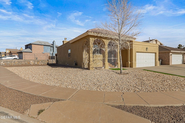 view of front facade with fence, concrete driveway, stucco siding, a garage, and a gate